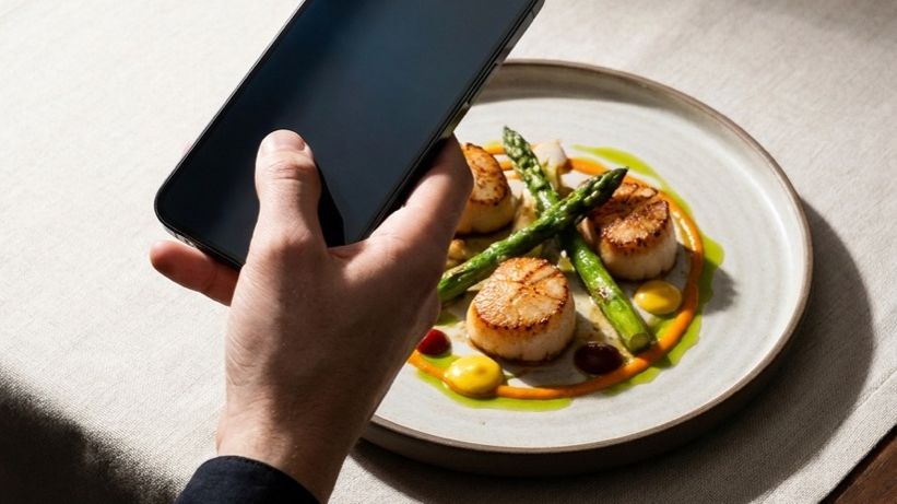 A phone held over a plate of food to photograph it for logging