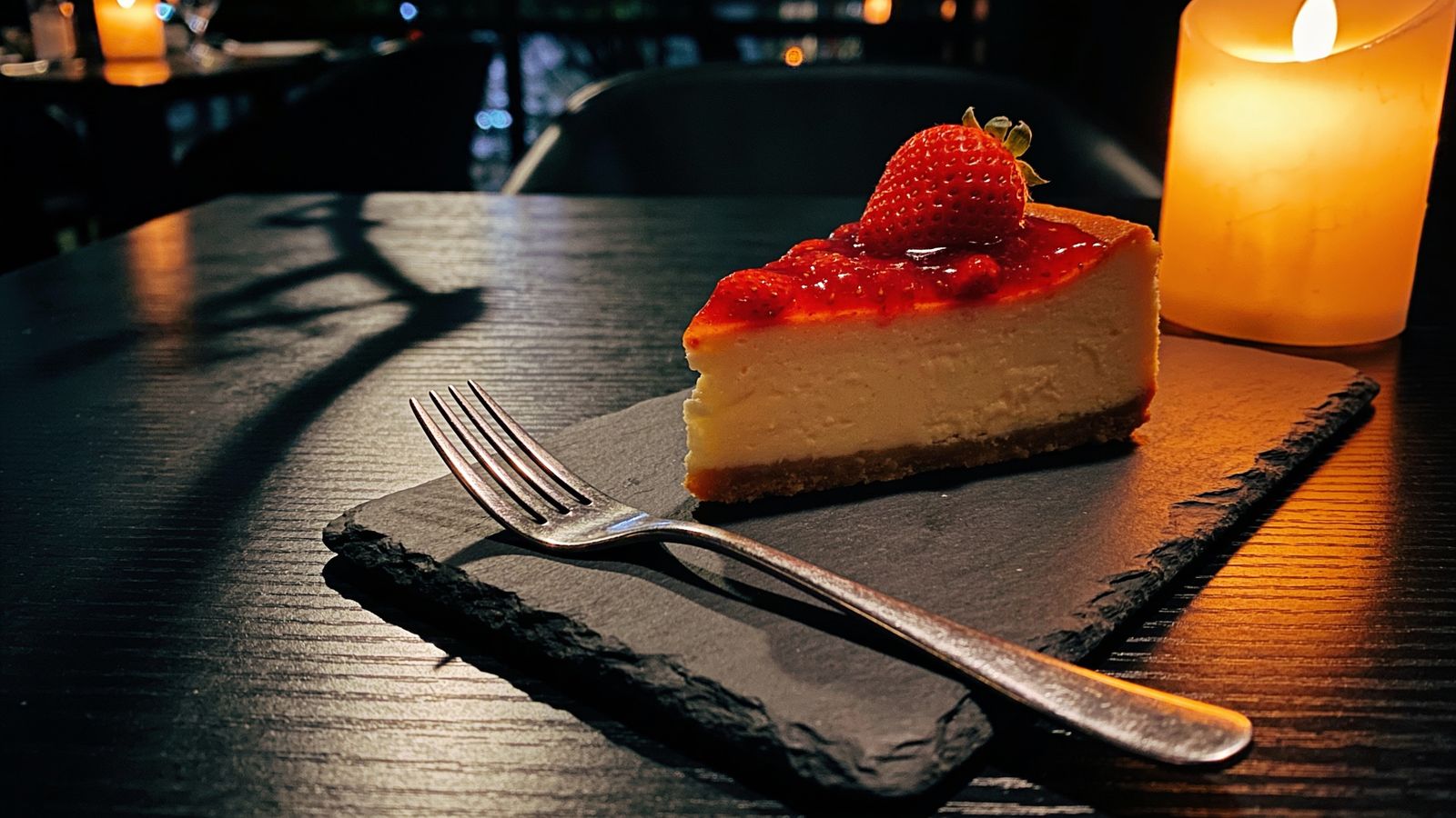 A slice of cheesecake on a plate at a restaurant table